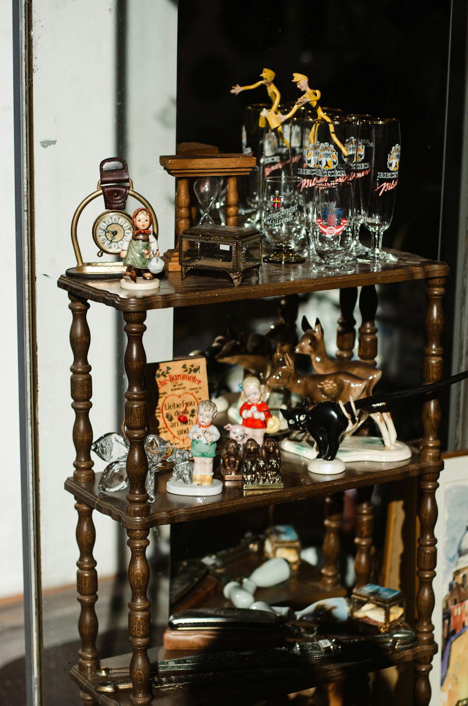 Scaffale in legno vintage con statuette in ceramica e oggetti da collezione d'antiquariato.
